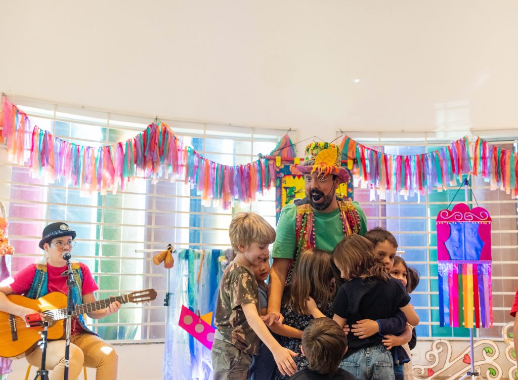 (13.maiI.23) - Edu recebe abraço coletivo das crianças durante contação de histórias na Biblioteca Áurea Alencar. Foto: Tero Queiroz | TeatrineTV 