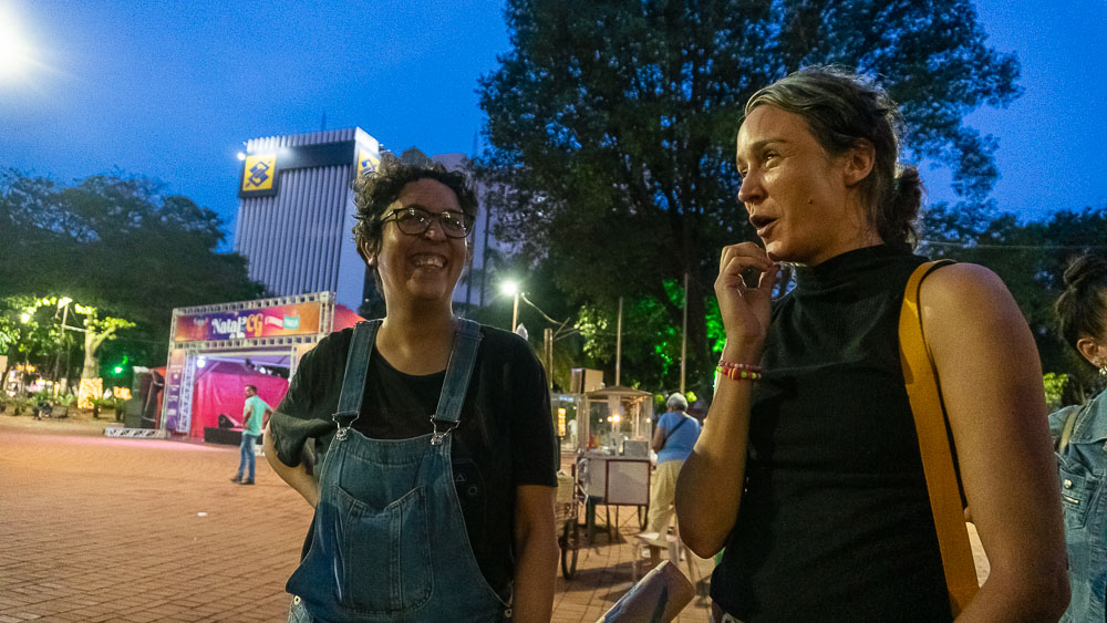 (15.dez.23) - À direita, Kitty conversa com companheira durante pausa na Praça Ary Coelho. Foto: Tero Queiroz 