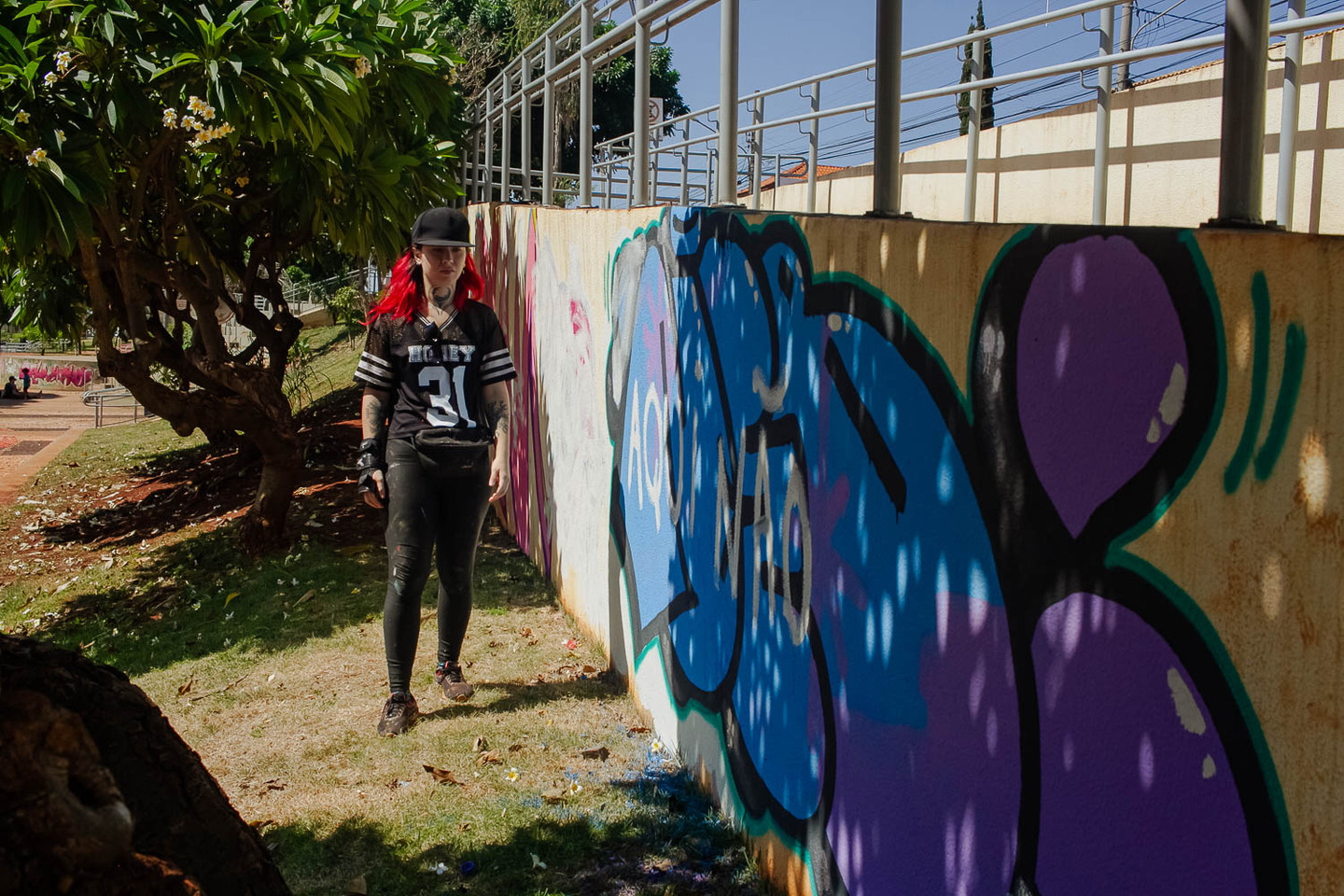 (1.fev.24) - Thais Maia caminha ao lado de mural destruído após ataque de presidente do bairro e outros dois homens. Foto: Tero Queiroz 