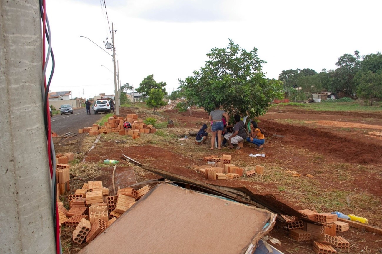 Famílias abrigam sobre árvores enquanto a chuva começa a cair no terreno em que estavam suas casas derrubadas por patrolas com a aval da prefeitura de Campo Grande.  Foto: Tero Queiroz