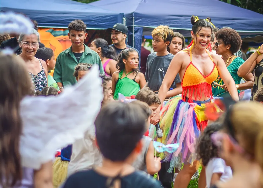 Angela Montealvão, de roupa colorida brincando com as crianças em ação na Feira Bosque da Paz. Foto: Wendel Fontes